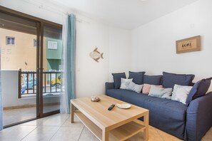 Un salon comprenant un canapé, une table basse et une porte-fenêtre coulissante donnant sur un espace extérieur.