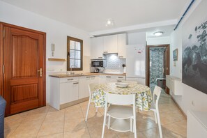 Une cuisine de taille réduite avec un coin repas, une porte en bois et un sol carrelé.
