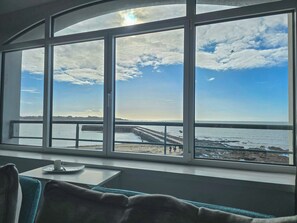 A room with a large window overlooking a beach and a pier. - Penthouse sea view - Patio & private parking (Concarneau)