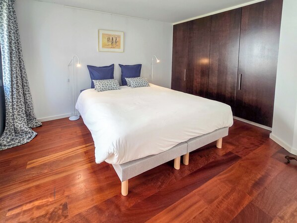 A bedroom with a large bed, dark wooden wardrobe, and a framed picture on the wall. - Penthouse sea view - Patio & private parking (Concarneau)