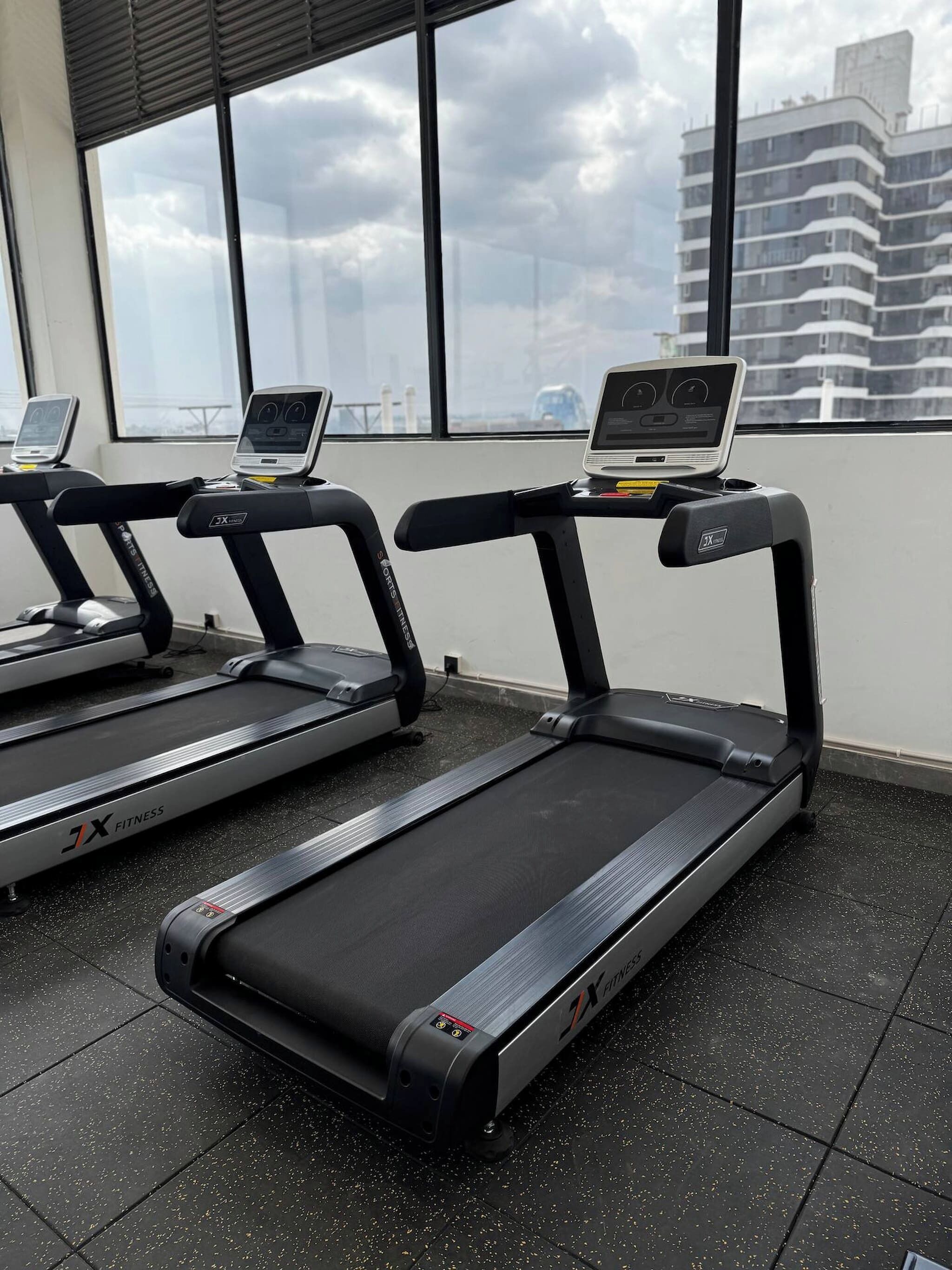 Une salle de sport avec des tapis de course, et un ordinateur portable posé sur l’un d’eux.