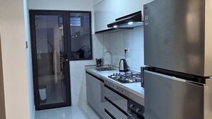 A modern kitchen with stainless steel appliances, a gas stove, and a refrigerator. - Brand New Westlands 1BR 1Ba Walk to Sarit GTC (Nairobi)