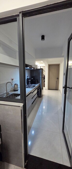 A modern kitchen with a stainless steel sink, a coffee maker, and a stove. - Brand New Westlands 1BR 1Ba Walk to Sarit GTC (Nairobi)