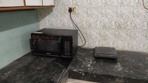 A microwave oven on a black countertop with a power strip plugged in.
