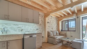 Eine moderne Küche mit Holzbalken, einer Steinwand und Blick ins Freie.