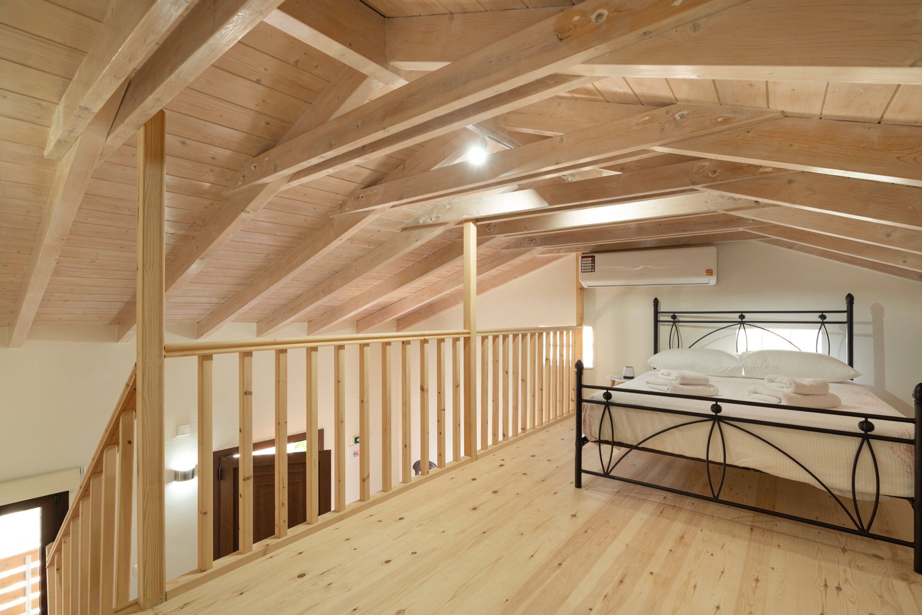 Ein Schlafzimmer mit Holzboden, Metallbettgestell und einer Holztreppe.