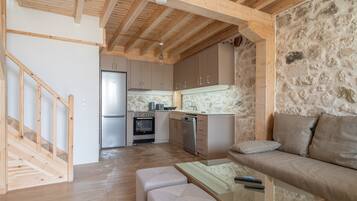 A modern kitchen with wooden beams, a stone wall, a sofa, and a glass table.