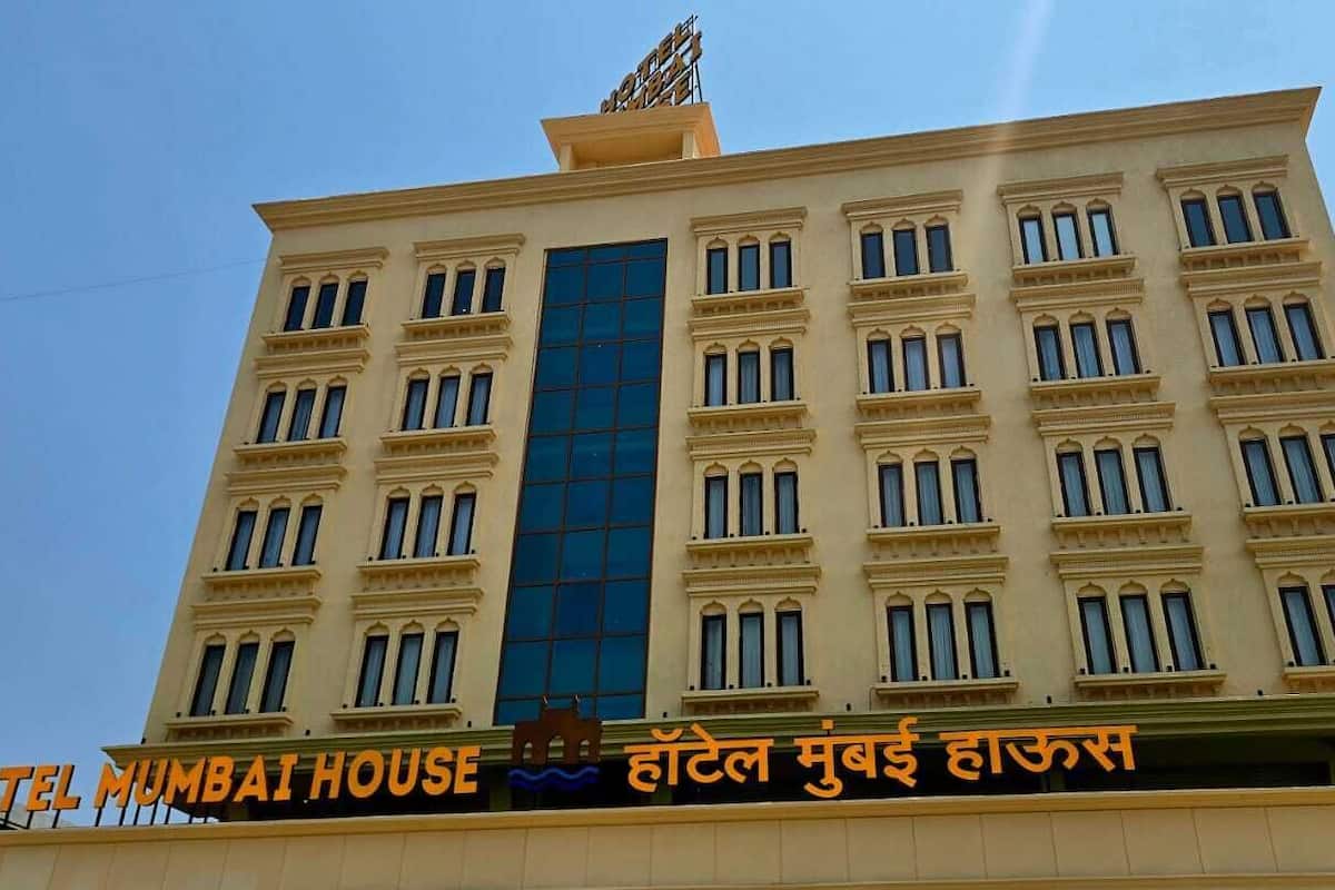 A multi-story building with a prominent sign reading 'HOTEL MUMBAI HOUSE' and another sign in a different script.