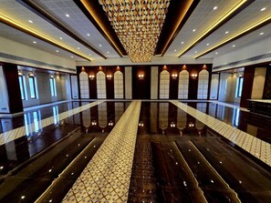 Eine großzügige Lobby mit einem spiegelnden Boden, einer imposanten Chandelier und bogenförmigen Fenstern.