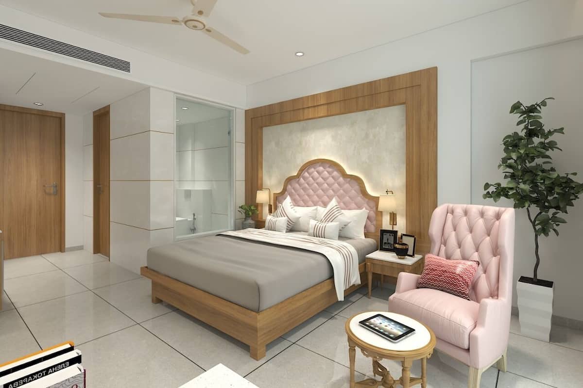 A modern bedroom with a large bed, bedside tables, a chair, a small table, and a potted plant.