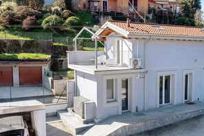 A white building with a balcony, a small attached structure, and a red-tiled roof. - 'Residenza La Fonte Dependance' – Perfect for Couples, Private Terrace, Air Conditioning (Laveno-Mombello)