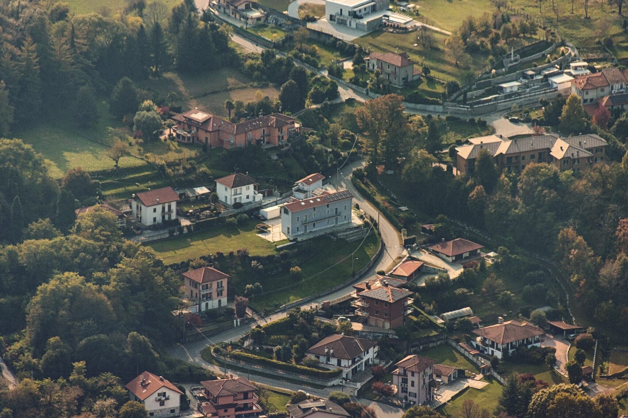 An aerial view of a residential area with houses, roads, and green spaces.