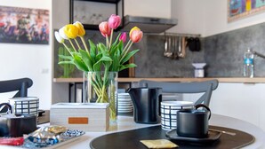Uma cozinha moderna com uma mesa de jantar posta para o chá, um vaso com tulipas e utensílios de cozinha.