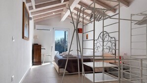 Quarto com cama, escrivaninha de madeira, cadeira e janela com vista para árvores.