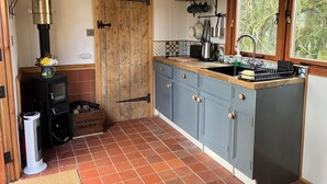 Una cocina compacta con puerta de madera, estufa integrada y ventana con vista a follaje.