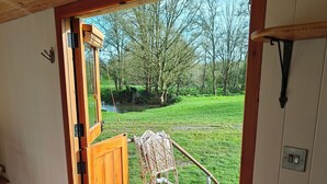 Una puerta de madera que da a un espacio al aire libre cubierto, con una silla y un extintor.