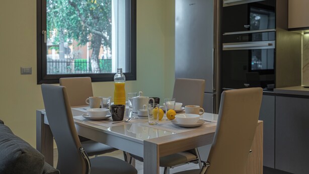A modern dining area with a table set for breakfast, including cups, a jug, and a lemon.