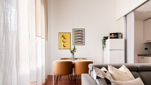 A modern living room with a grey sofa, a dining table with chairs, and artwork on the wall. - Garibaldi - Modern 1 BR in Brera by Rentopolis (Milano)