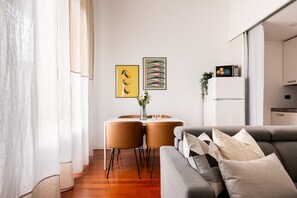 A modern living room with a grey sofa, a dining table with chairs, and artwork on the wall. - Garibaldi - Modern 1 BR in Brera by Rentopolis (Milano)