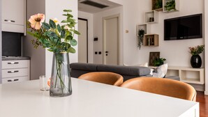 A modern living room with a white sofa, a glass vase with flowers, and a flat-screen TV mounted on the wall. - Garibaldi - Modern 1 BR in Brera by Rentopolis (Milano)