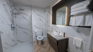 Ein modernes Badezimmer mit einer Duschkabine, einer Toilette, einem Waschtisch und einem Handtuchhalter.