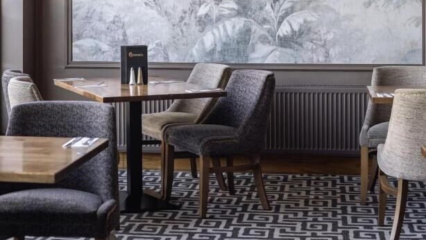 Ein Restaurantinneres mit einem großen Wandgemälde, Holztischen und gepolsterten Stühlen.