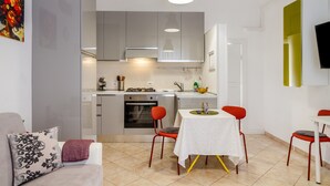 A modern kitchen with grey cabinets, a dining area with a table and chairs, and a TV mounted on the wall.