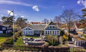 A large house with a spacious patio, a swimming pool, and a well-maintained garden.