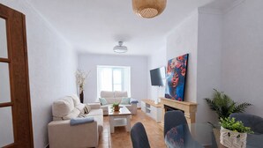 Ein modernes Wohnzimmer mit einer Couch, einem Glastisch und einem an der Wand befestigten Fernseher.