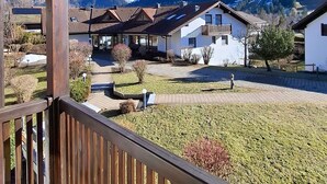Een houten balkon met uitzicht op een dorp, huizen en bergen.