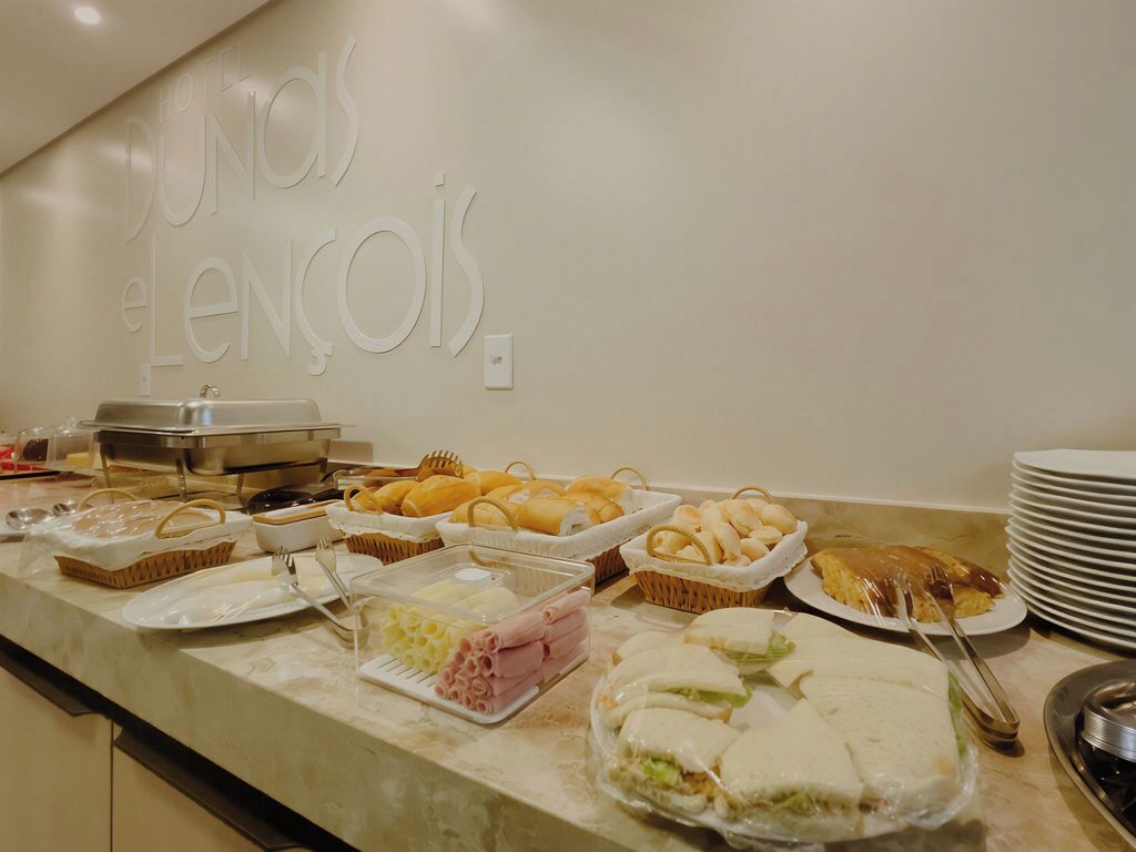A buffet counter with various food items and a sign reading "Dundas e Lencois".