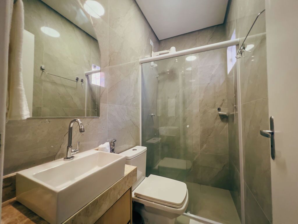 A modern bathroom with a large sink, toilet, and glass-enclosed shower.