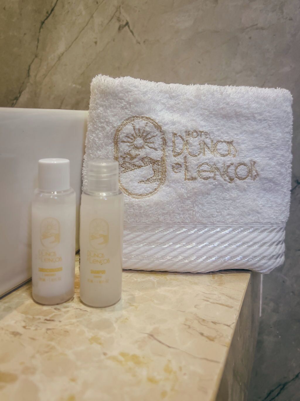 A bathroom with a white towel and two bottles of lotion on a marble countertop.