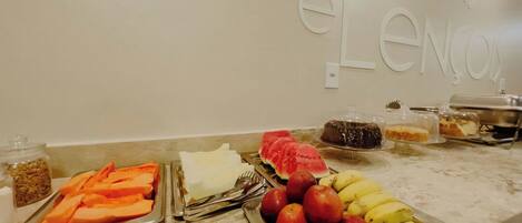 A buffet with various fruits and desserts on a marble countertop.