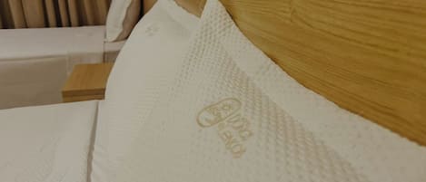 Una cama con cabecera de madera y almohada de superficie texturizada.