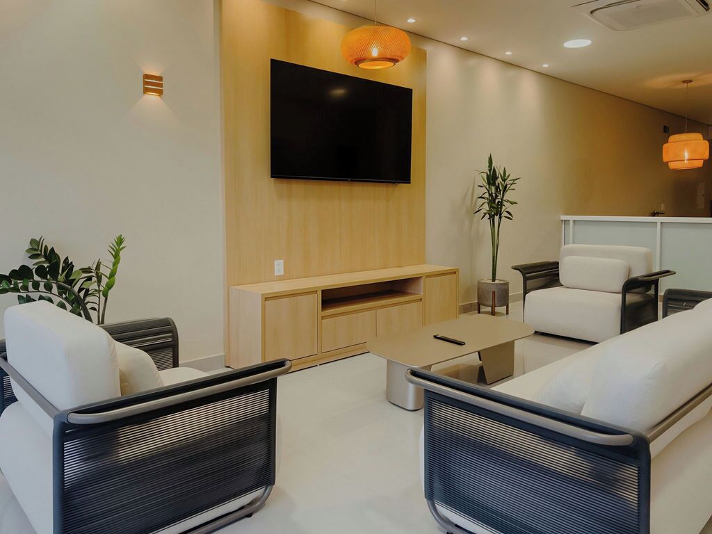A modern living room with a flat-screen TV mounted on the wall, a wooden entertainment unit, and a seating area with two sofas and a coffee table.