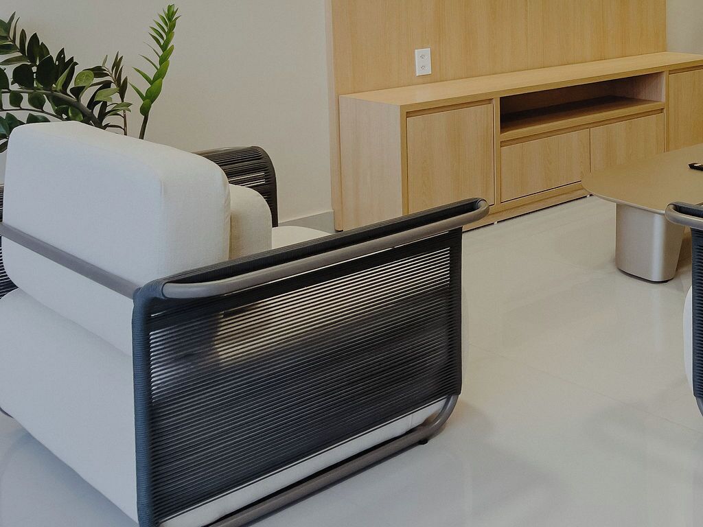 A modern living room with a white sofa, a black chair, and a wooden cabinet.