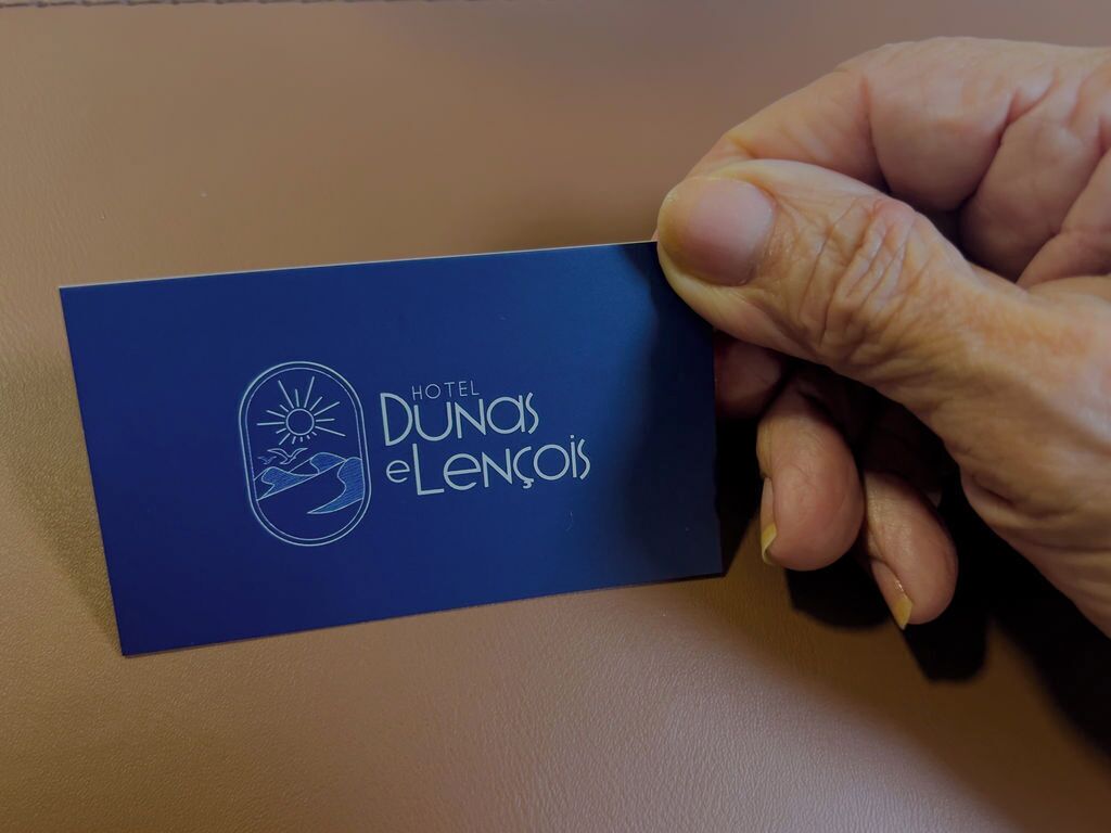 Una mano sostiene una tarjeta de presentación del HOTEL DUNOS ELENCOIS.