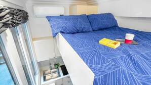 Une petite pièce comprenant un lit superposé, un coin cuisine et une fenêtre avec des rideaux.