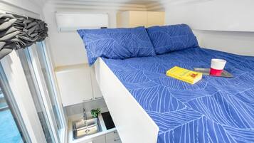Une petite pièce comprenant un lit superposé, un coin cuisine et une fenêtre avec des rideaux.