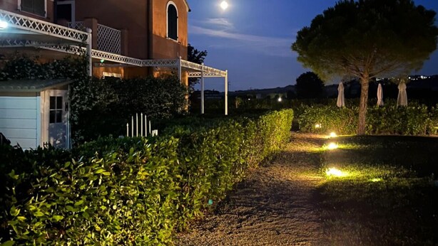 A building with a covered porch, a tree, and a pathway lit by ground lights.