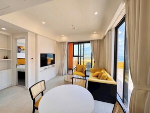 A modern living room with a television, a round dining table, and a sofa with cushions. - Luxury Hillside Apartment Phu Quoc by H House Sunset Town (Phu Quoc)