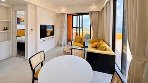 A modern living room with a TV, sofa, and dining table. - H House Apartment Phu Quoc (Phu Quoc)