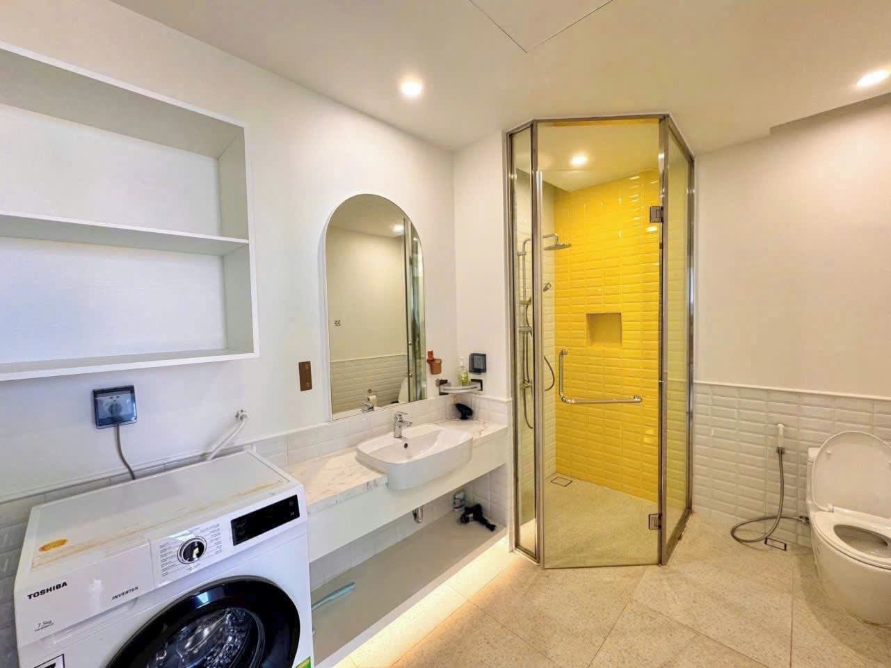 Un baño moderno con ducha envuelta en vidrio, lavadora e inodoro.