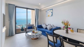 A modern living room with a blue sofa, a round coffee table, and a dining table. - H House Apartment Phu Quoc (Phu Quoc)