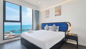 A hotel room with a large bed, a nightstand, and a view of the sea. - H House Apartment Phu Quoc (Phu Quoc)