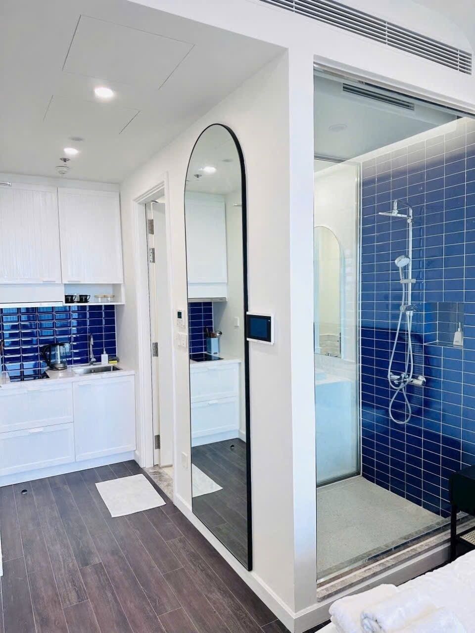A modern bathroom with a glass-enclosed shower, a white vanity, and a blue-tiled shower wall.