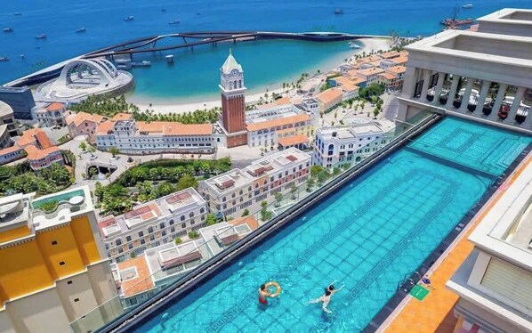 A hotel with a swimming pool, a beach, and a tower. - Luxury Hillside Apartment Phu Quoc by H House Sunset Town (Phu Quoc)