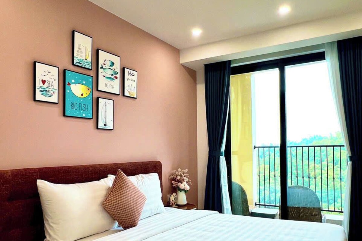 A hotel room with a bed, a window with curtains, and wall art.
