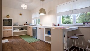 Una cocina moderna con armarios de madera, lavavajillas, microondas y un ventanal grande.